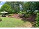 A lush backyard features a patio area, mature trees, and professional landscaping at 521 Morning Oaks Dr, Holly Springs, NC 27540