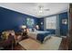 A stylish bedroom boasts a blue accent wall, a ceiling fan, and a cozy leather chair at 521 Morning Oaks Dr, Holly Springs, NC 27540