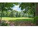 View of the golf course through mature shade trees at 521 Morning Oaks Dr, Holly Springs, NC 27540