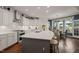 Sun-filled kitchen boasts an island with seating, granite countertops, white cabinets, and a view to the backyard at 521 Morning Oaks Dr, Holly Springs, NC 27540