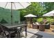 Relaxing patio with a dining table, lounge chairs, umbrellas, and well-manicured landscaping create a serene outdoor space at 521 Morning Oaks Dr, Holly Springs, NC 27540