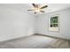 Cozy bedroom with carpet, a ceiling fan, and a window overlooking a wooded area at 5500 Lake Wendell Rd, Zebulon, NC 27597
