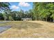 A beautiful single-story home with light gray siding surrounded by lush trees at 5500 Lake Wendell Rd, Zebulon, NC 27597
