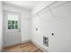 Bright laundry room with wood flooring, white door, and ample shelving for storage at 5500 Lake Wendell Rd, Zebulon, NC 27597