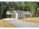 View of the back and side of a gray, single-story home with carport and gravel driveway at 5500 Lake Wendell Rd, Zebulon, NC 27597