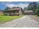 Log home with long front porch and an oversized detached garage on a gravel driveway at 5593 Leon Rd, Nashville, NC 27856
