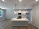 Modern kitchen featuring a large center island, stylish pendant lighting, and sleek white cabinetry at 57 Blanton Ct, Lillington, NC 27546