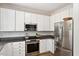 White kitchen featuring stainless appliances, granite countertops, and ample cabinet space at 5833 Dahlberg Dr, Raleigh, NC 27603
