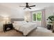 Calming main bedroom with neutral tones, ceiling fan, and a window overlooking lush greenery at 5833 Dahlberg Dr, Raleigh, NC 27603