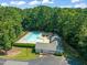 An aerial view of community pool featuring a sparkling pool, sun loungers, and clubhouse surrounded by green trees at 6051 Epping Forest Dr, Raleigh, NC 27613