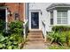 Charming home front entrance with brick steps leading to the black front door, complemented by lush greenery at 6051 Epping Forest Dr, Raleigh, NC 27613