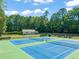 A community tennis court area with blue courts and green surrounds, shaded by tall trees under a blue sky at 6051 Epping Forest Dr, Raleigh, NC 27613