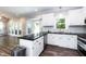 Stylish kitchen with stainless steel appliances, white cabinets, island with dark countertop, and a view to a sunroom at 6205 Remington Lake Dr, Raleigh, NC 27616