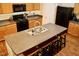 Close-up view of the kitchen island featuring a sink and seating, complemented by wooden cabinetry at 642 Collington Dr, Mebane, NC 27302