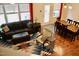 Bright living room with dark leather furniture, geometric rug, and dining area near windows with backyard view at 642 Collington Dr, Mebane, NC 27302