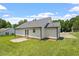 Rear view of home with a large grassy backyard, patio and white vinyl siding at 65 Alcock Ln, Youngsville, NC 27596