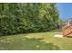 Large backyard with mature trees, a green lawn, and a wood deck for outdoor enjoyment at 733 Bluffcreek Dr, Fuquay Varina, NC 27526