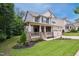 Two-story home with a covered porch and stone accents, complemented by a lush lawn and mature trees at 733 Bluffcreek Dr, Fuquay Varina, NC 27526