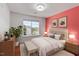 Staged bedroom boasts a big window and colorful pink wall with decor at 7414 Brandon Allen Ave, Raleigh, NC 27613