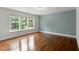 Spacious bedroom featuring hardwood floors and three large windows overlooking the backyard at 7414 Brandon Allen Ave, Raleigh, NC 27613