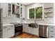Well-appointed kitchen featuring stainless appliances, light gray cabinets, a farmhouse sink, and wooden shelves at 7414 Brandon Allen Ave, Raleigh, NC 27613