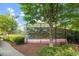 Well-maintained tennis court enclosed by fencing, surrounded by greenery and landscaping along a paved path at 7414 Brandon Allen Ave, Raleigh, NC 27613
