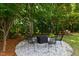 Landscaped backyard featuring a stone firepit area with seating, perfect for outdoor entertaining and relaxation at 8205 Rolling Glenn Dr, Raleigh, NC 27616