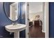 Stylish half bathroom with a pedestal sink, round mirror, and rich blue accent wall at 8205 Rolling Glenn Dr, Raleigh, NC 27616