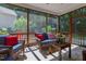 Relaxing screened porch featuring wicker seating, a wooden coffee table, and a pleasant view of the outdoors at 8205 Rolling Glenn Dr, Raleigh, NC 27616