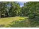 Expansive backyard features lush green lawn with playground and mature trees offering shade and privacy at 860 Cokesbury Rd, Fuquay Varina, NC 27526