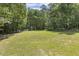 Expansive backyard features lush green lawn with playground and mature trees offering shade and privacy at 860 Cokesbury Rd, Fuquay Varina, NC 27526