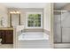 Bathtub in a bathroom featuring tan-colored walls, a granite-topped vanity, and a shower at 860 Cokesbury Rd, Fuquay Varina, NC 27526