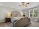 Bright main bedroom with a ceiling fan, side tables, and a large window overlooking greenery at 860 Cokesbury Rd, Fuquay Varina, NC 27526