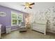 Bedroom featuring a floral accent wall, a crib, a comfortable chair, and a large window at 860 Cokesbury Rd, Fuquay Varina, NC 27526