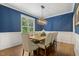 Dining room featuring blue walls with white trim, hardwood floors and elegant lighting at 860 Cokesbury Rd, Fuquay Varina, NC 27526