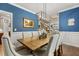 Dining room with blue walls, hardwood floors, modern chandelier, and seating for eight at 860 Cokesbury Rd, Fuquay Varina, NC 27526