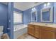 Bright bathroom featuring double sinks with wood cabinetry and a large soaking tub at 1144 Dexter Ridge Dr, Holly Springs, NC 27540