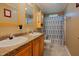 Well-lit bathroom with double sinks, wood cabinets, decorative mirror, and tiled shower with patterned curtain at 125 Green Ln, Clayton, NC 27520