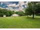 Picturesque view of a well-manicured lawn with a charming house, mature trees, and outbuildings at 125 Green Ln, Clayton, NC 27520