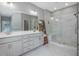 Modern bathroom featuring a glass-enclosed shower, double vanity, and stylish gray cabinets and marble-look flooring at 128 Chapel Run Way, Chapel Hill, NC 27517