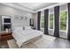 Sun-filled bedroom with stylish decor, featuring a plush white bed and large windows with dark curtains at 128 Chapel Run Way, Chapel Hill, NC 27517