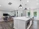 Open-concept kitchen features an island with stainless steel appliances, modern lighting and flows into the living area at 128 Chapel Run Way, Chapel Hill, NC 27517