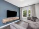 Cozy living room featuring a plush gray sofa, floating wood media console, and natural light from large windows at 128 Chapel Run Way, Chapel Hill, NC 27517