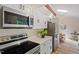 Kitchen featuring stainless appliances, white cabinetry, quartz countertops, and a view to an eat-in dining area at 1403 Meadow Ln, Chapel Hill, NC 27516