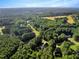Distant aerial view of a quiet residential neighborhood with homes nestled among lush green trees and open fields at 1515 Bradsher Dr, Stem, NC 27581