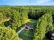 Aerial view of a charming single-story home surrounded by lush greenery and tall trees in a serene setting at 1515 Bradsher Dr, Stem, NC 27581