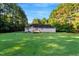 Expansive backyard view showcasing the house's rear, deck, and surrounding trees at 1515 Bradsher Dr, Stem, NC 27581