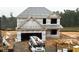Two-story house under construction with visible framing, a two-car garage, and construction equipment nearby at 20 Malbec Way, Youngsville, NC 27596