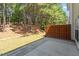 View of backyard with concrete patio, short retaining wall, and mature trees beyond at 3021 Winding Waters Way, Raleigh, NC 27614
