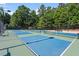 Multiple, community pickleball courts with blue surface and green trim surrounded by trees and fencing at 3021 Winding Waters Way, Raleigh, NC 27614